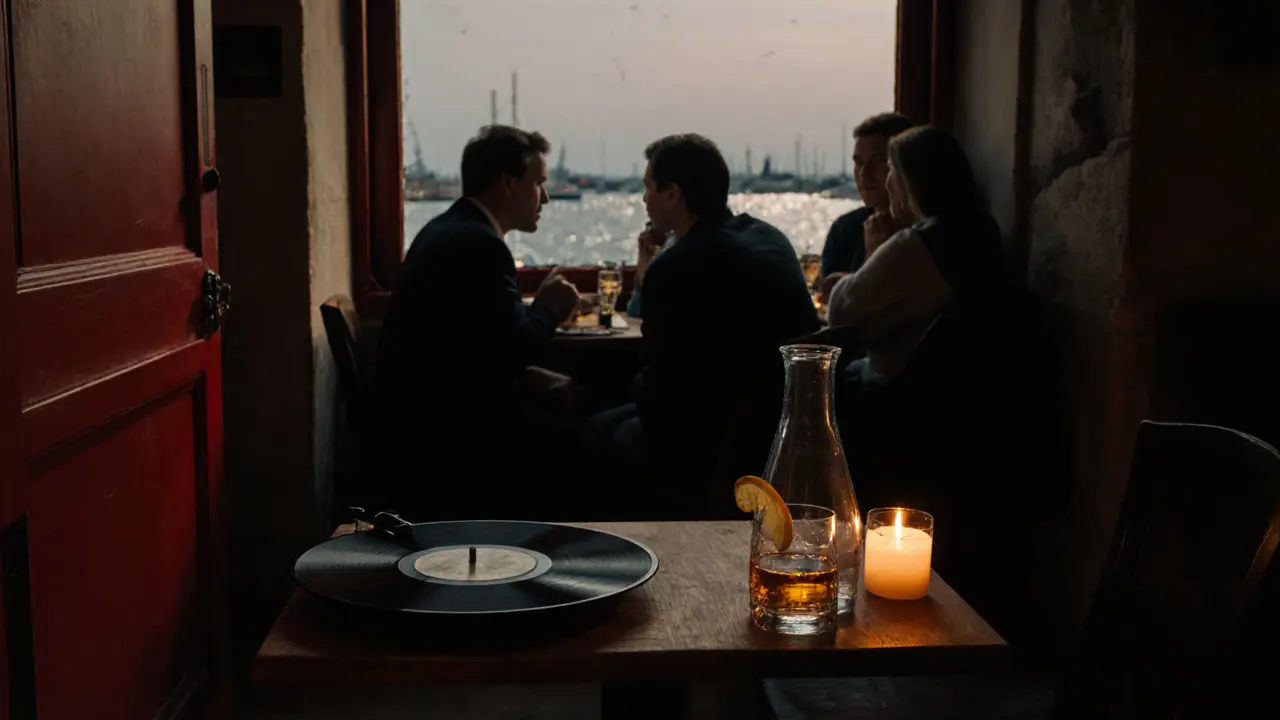 An intimate after-hours spot behind the port, with a vinyl record, whiskey glass, and tap water under candlelight.